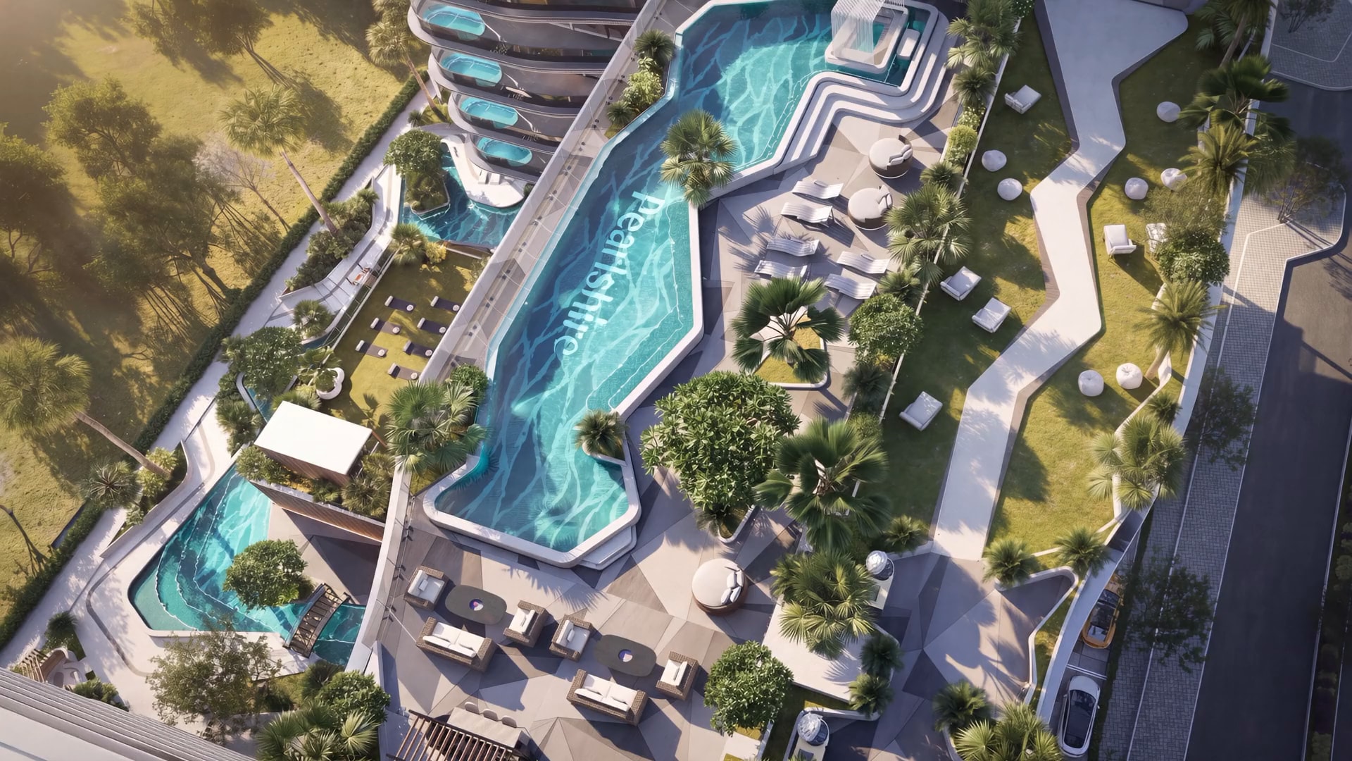 Aerial view of the Bond Enclave garden at golden hour, the lazy pool curving past palms and loungers